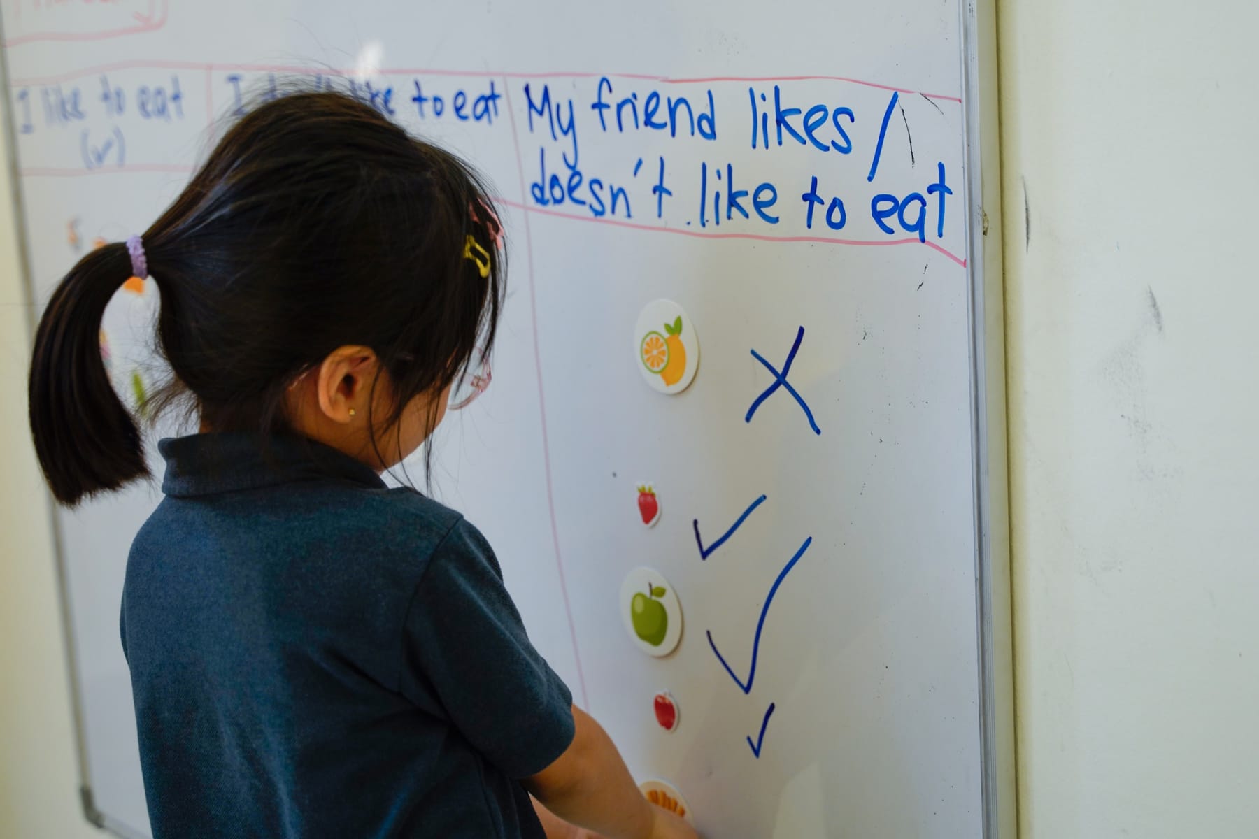 A six year old writing English sentences on the whiteboard