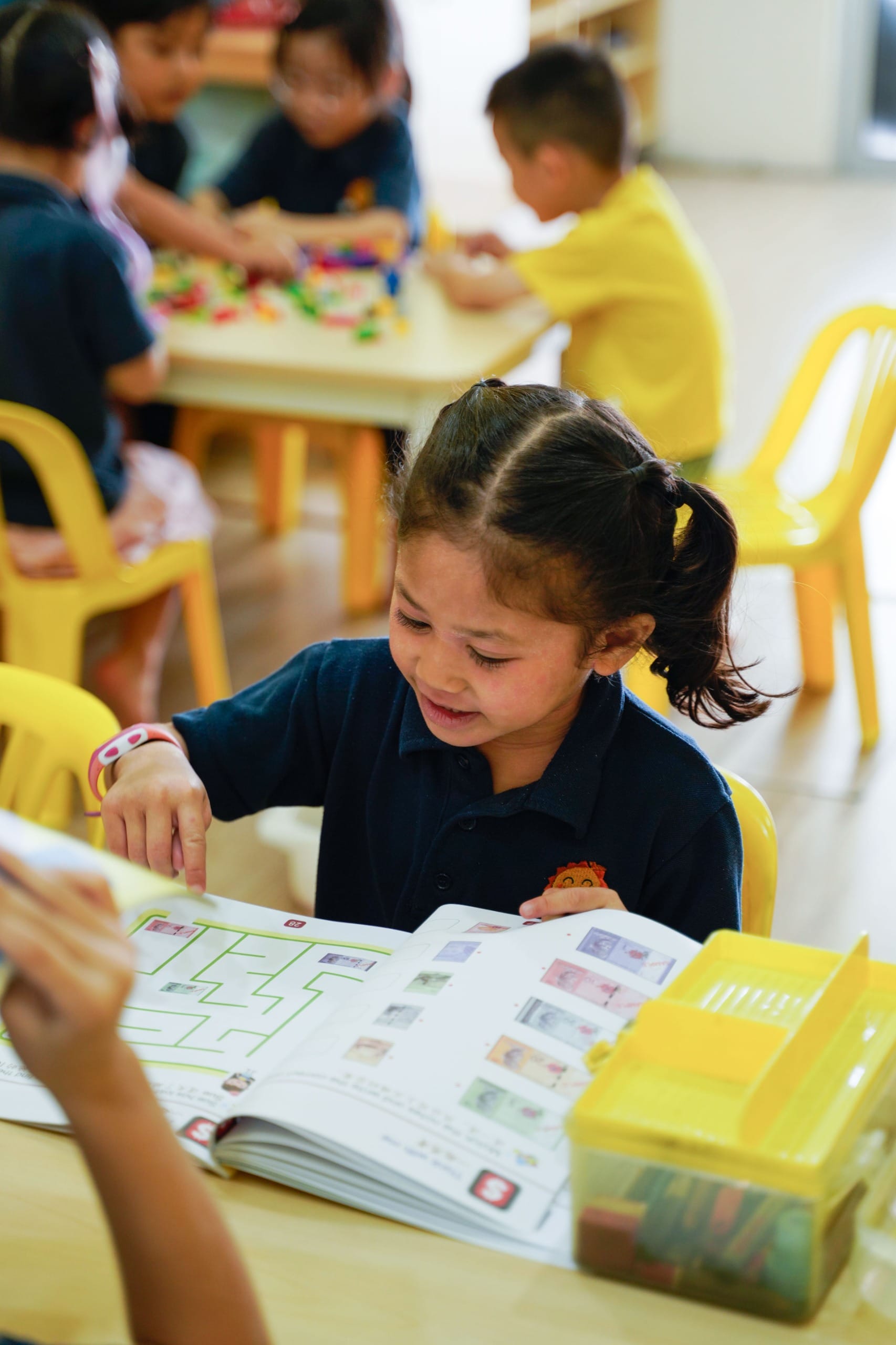 A SunnySeeds kindergarten girl smiling as she works through a maze in her activity book