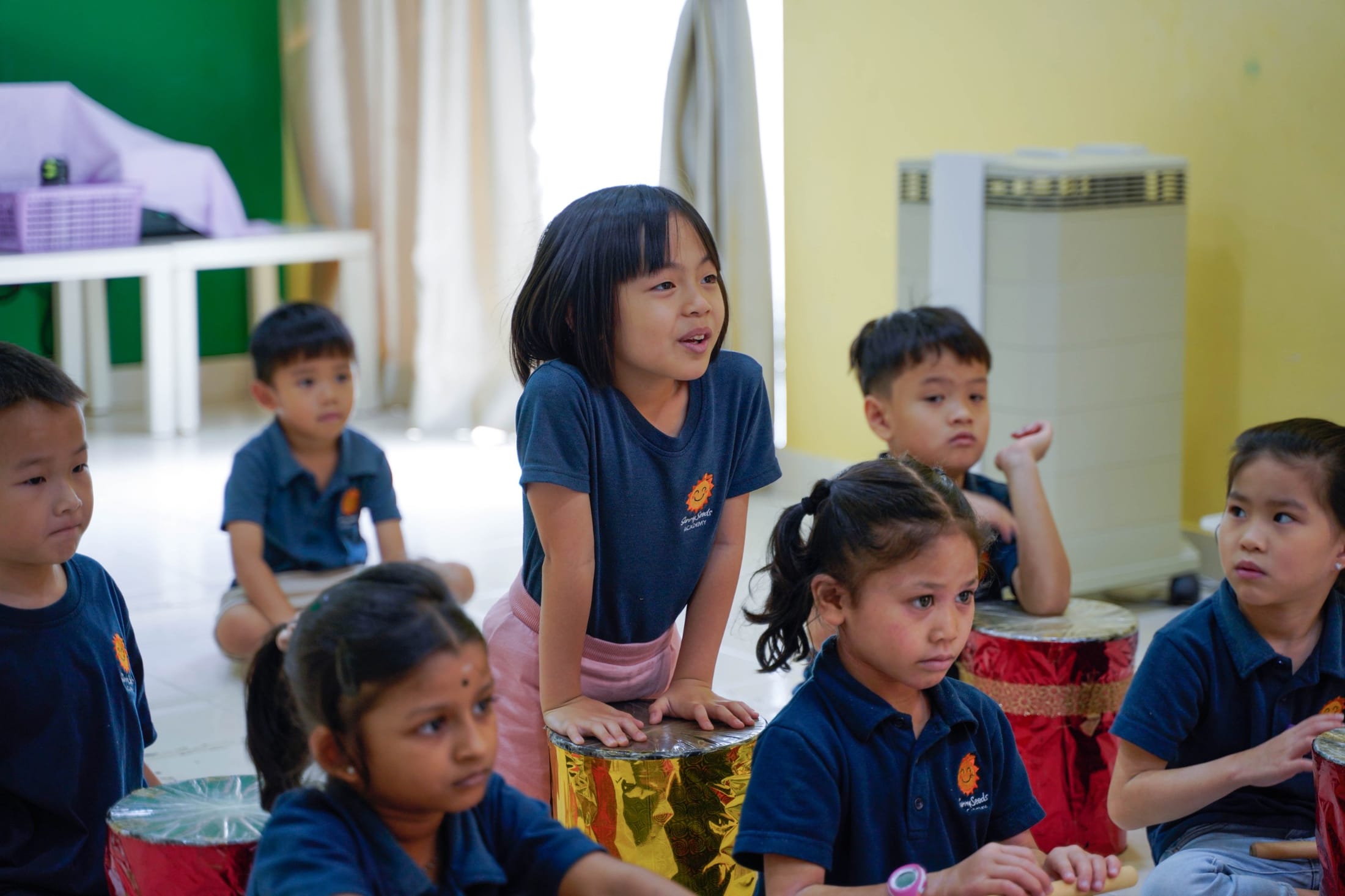 Children gathered around drums during a music session