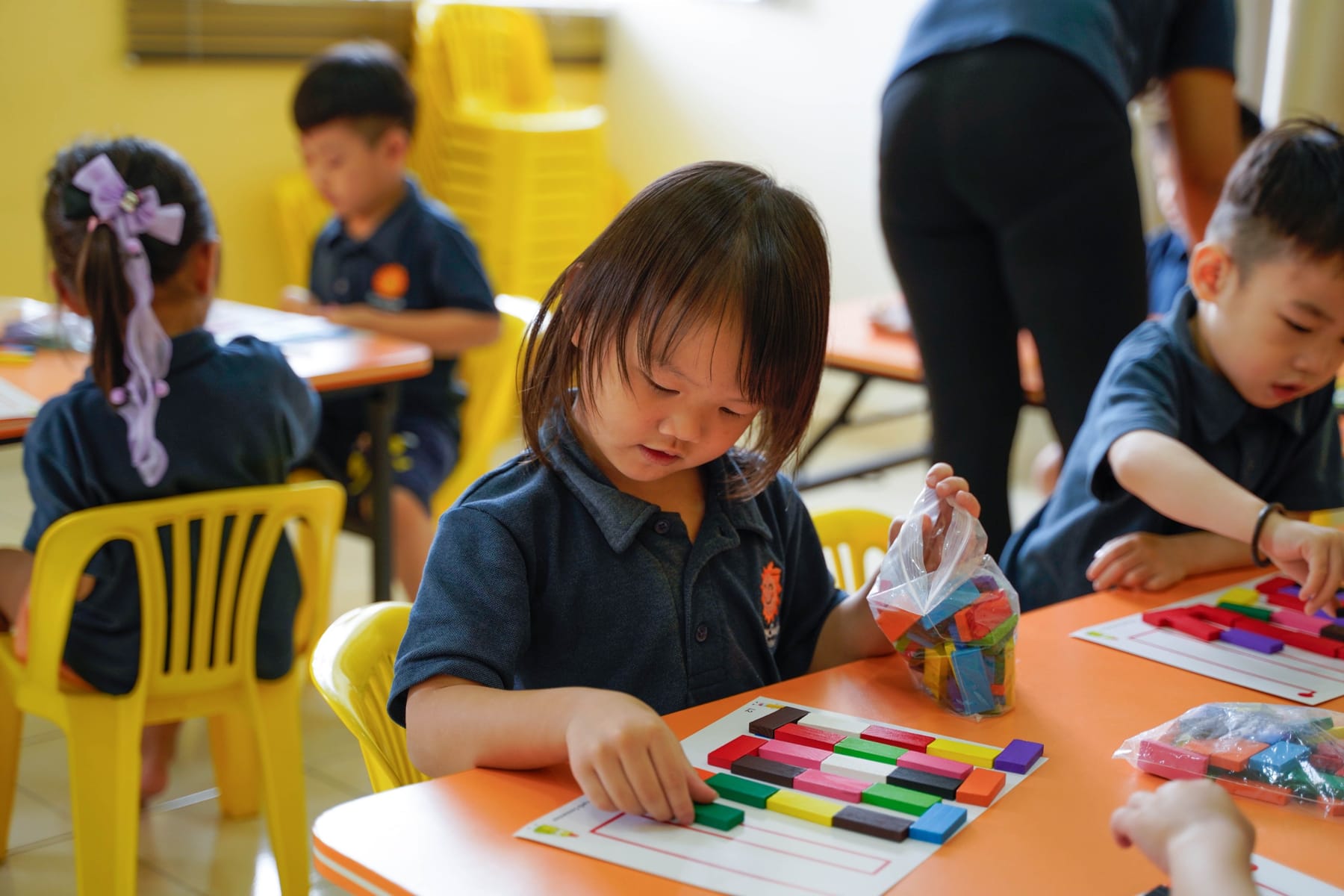 A preschool girl sorting coloured number rods